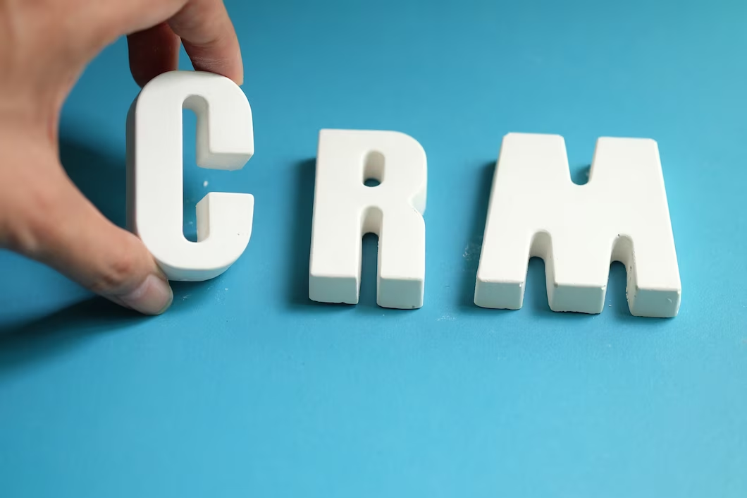 Photograph of a hand arranging white letters to spell 'CRM'