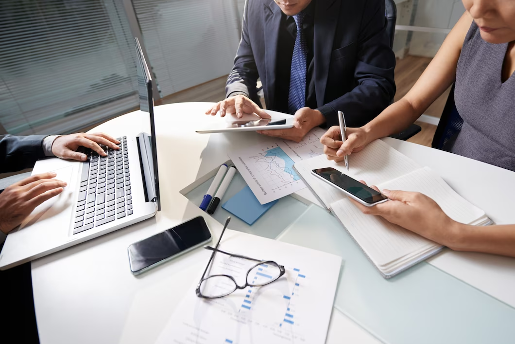 Three people gathered around a table with office reports and business documents